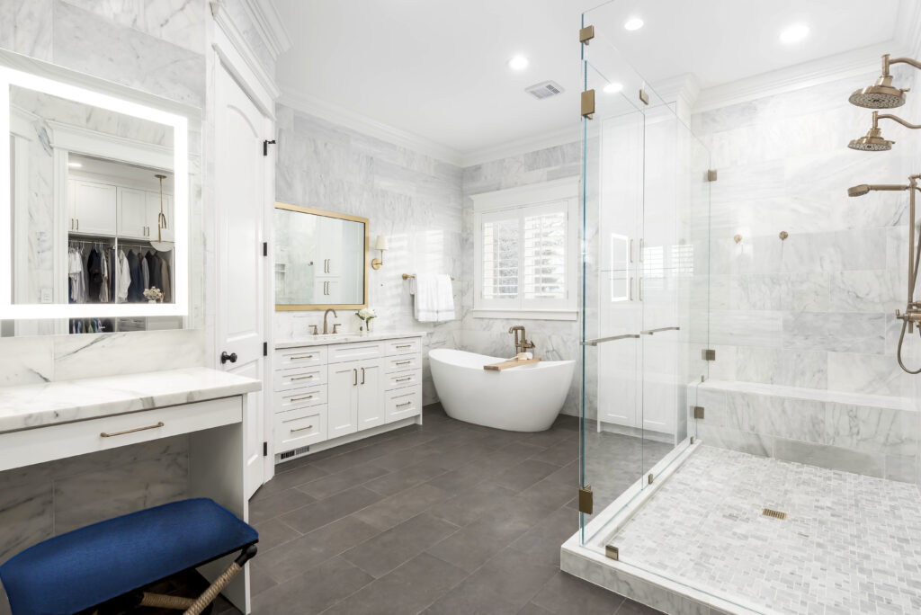 Marble tiled shower featuring built in bench, mosaic tile shower floor, brushed brass fixtures, and frameless glass enclosure.