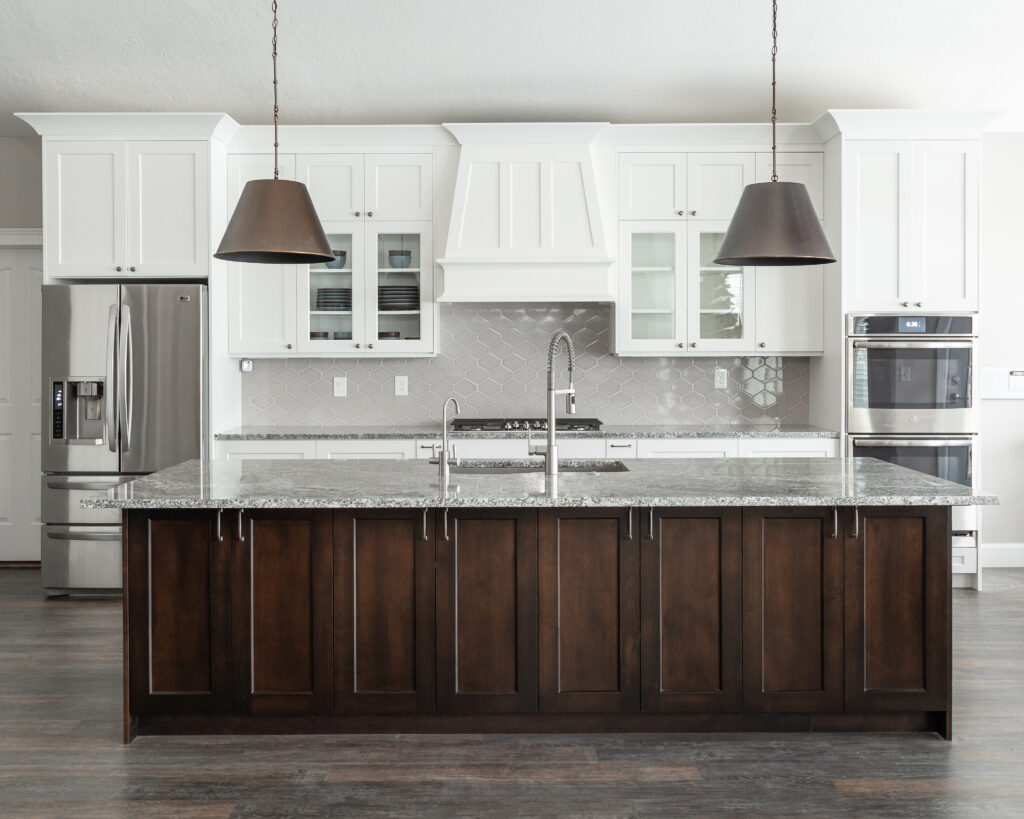 Bright kitchen with white shaker cabinets, custom range hood surround, granite countertops, and hexagon tile backsplash.