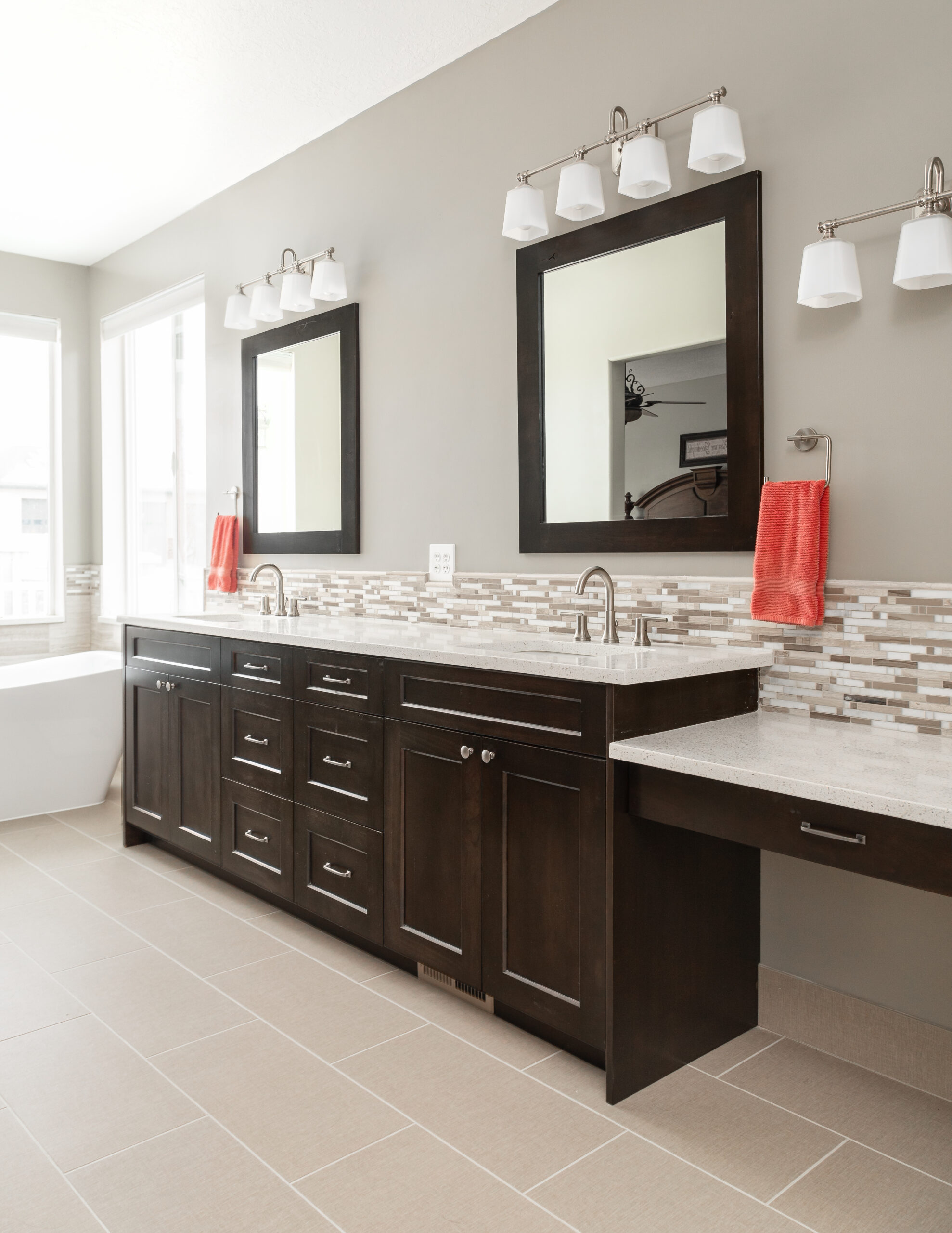 Dark wood bathroom vanity with quartz countertop, mosaic tile backsplash, wall mirrors, and modern vanity lighting.